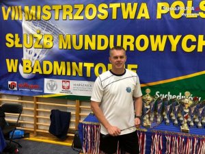 asp. sztab. Dariusz Opatrzyk na tle pucharów i medali