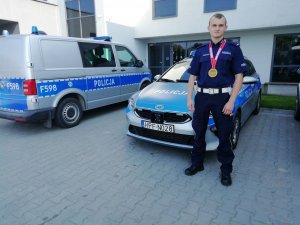 Policjant z medalem przy radiowozie
