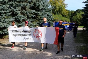 Uczestnicy w trakcie biegu trzymający baner Olimpiad Specjalnych.