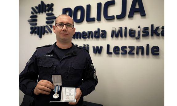 Sierżant sztabowy Tomasz Kowalski z Komendy Miejskiej Policji w Lesznie trzyma w ręku odznaczenie i legitymację