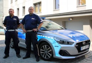 Policjanci, którzy uratowali mężczyznę stoją na tle radiowozu.