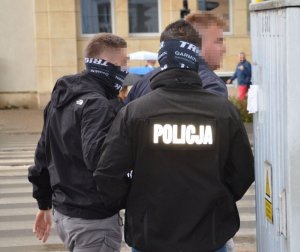 Policjanci trzymają zatrzymanego mężczyznę