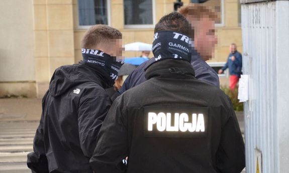 Policjanci trzymają zatrzymanego mężczyznę