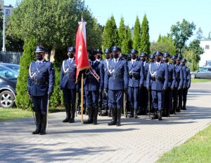 Policjanci stoją ze sztandarem