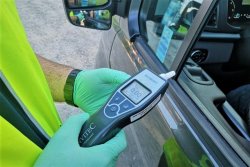 policjant trzyma w ręku alcoblow stojąc przy otwartym oknie kontrolowanego auta