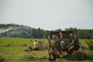 mężczyźni podczas rekonstrukcji siedzą obok armaty