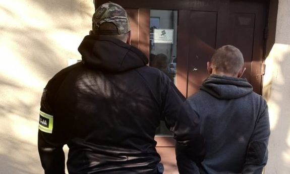 policjant prowadzi zatrzymanego
