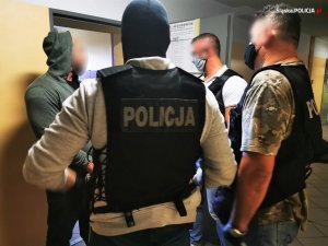 Trzej policjanci stoją z osobą zatrzymaną