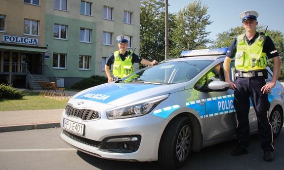 dwaj umundurowani policjanci ruchu drogowego stoją przy radiowozie