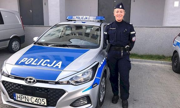 umundurowana policjantka stoi przy radiowozie