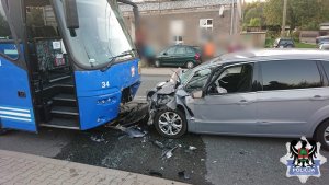 Na zdjęciu znajduje się samochód marki ford oraz autobus miejski.Oba samochody  mają mocno uszkodzony przód