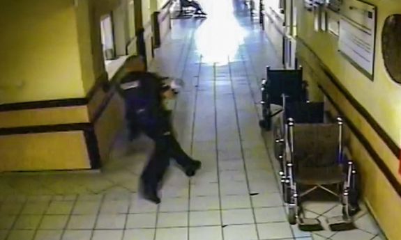 Policjant z dzieckiem na rękach biegnie po szpitalnym korytarzu&quot;&gt;