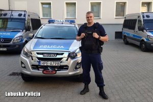 policjant stoi przed radiowozem