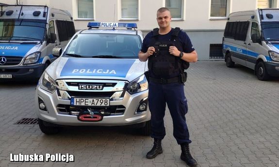 policjant stoi przed radiowozem