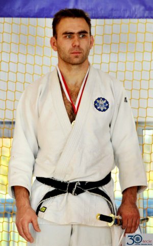 Policjant z medalem na szyi ubrany w strój do ćwiczeń Judo.