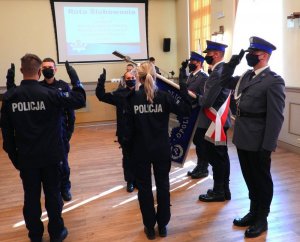 Policjanci podczas ślubowania obok stoją policjanci ze sztandarem