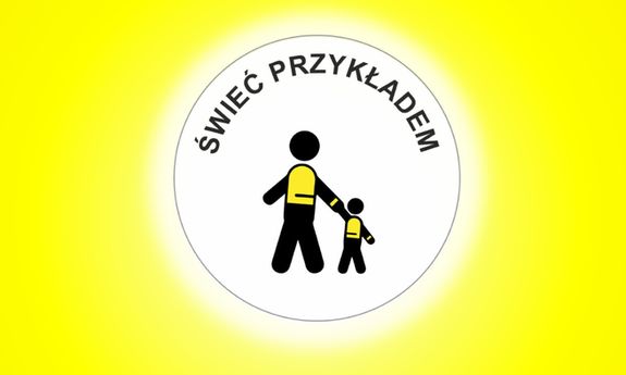 na żółtym tle białe kółko a w nim czarny napis: świeć przykładem, dwa czarne ludziki ubrane w kamizelki z elementami odblaskowymi