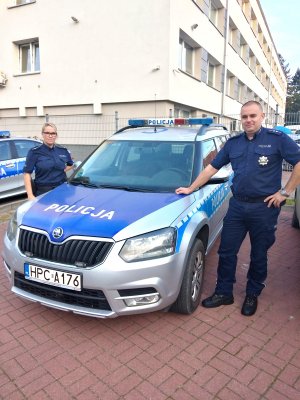 dzielnicowa młodszy aspirant Joanna Wesołowska i dzielnicowy aspirant Michał Kaczorowski stoją obok radiowozu na parkingu