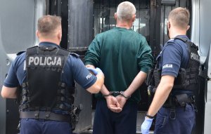 Policjanci prowadzą zatrzymanego