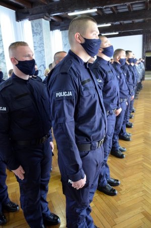 policjanci stoją w rzędach, na twarzy mają złożone maseczki ochronne