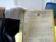 policjant trzyma zabezpieczone dokumenty z okresu II wojny światowej