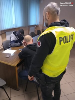 policjant stoi przy zatrzymanym mężczyźnie&quot;&gt;