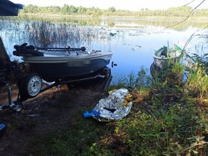 Łódź policjanta i łódź wędkarza na brzegu jeziora