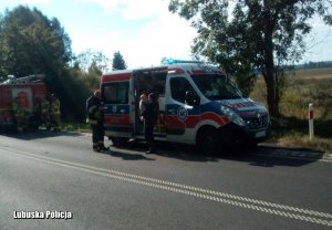 Policjantka z dzieciątkiem na ręku stoi przy ambulansie