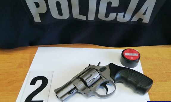 Zabezpieczona broń leży na stole z tyłu napis Policja