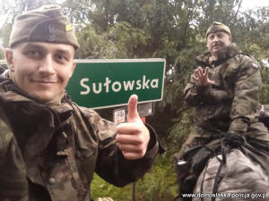 sierżant Marcin Dardziński wraz z zaprzyjaźnionym właścicielem stajni Robertem Karbowniczakiem przy znaku drogowym z nazwą miejscowości Sułowska