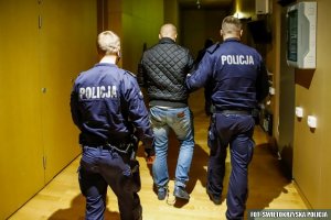 Policjanci prowadzą zatrzymanego na sale rozpraw