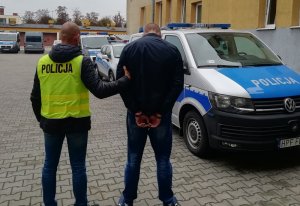 Policjant prowadzi zatrzymanego mężczyznę