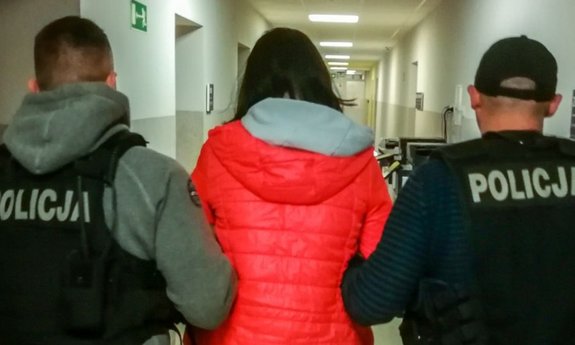 Policjanci prowadzący zatrzymaną kobietą