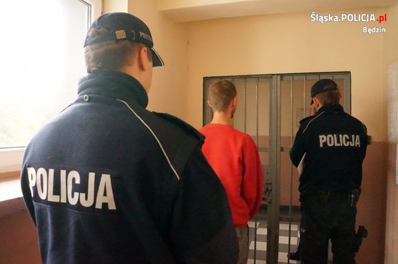 policjanci prowadzą zatrzymanego mężczyznę do policyjnej celi