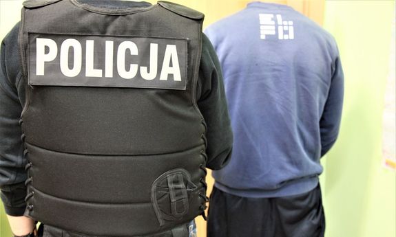 Policjant prowadzi zatrzymanego mężczyznę