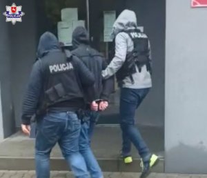 Zatrzymany jest prowadzony przez policjantów do tymczasowego aresztu