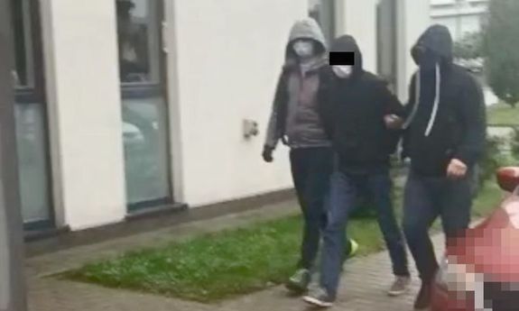 Policjanci prowadzą zatrzymanego do tymczasowego aresztu
