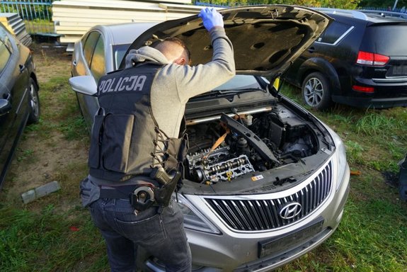 Policjant stojący przy otwartej masce jednego z samochodów