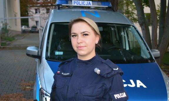 Policjantka, która zatrzymała nietrzeźwego kierowcę, stoi przed radiowozem.