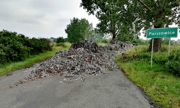 śmieci wyrzucone na środku drogi prowadzącej do miejscowości Parszowice, o czym świadczy znak z oznaczeniem miejscowości