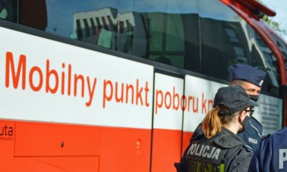 Policjanci czekający na oddanie krwi, a w tle krwiobus