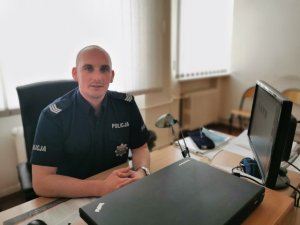 Umundurowany policjant siedzi przy biurku