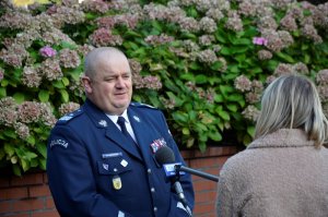 Komendant Wojewódzki Policji w Gdańsku nadinsp. Andrzej Łapiński (stoi przodem) udziela wywiadu przed budynkiem, przed nim stoi dziennikarka (tyłem)