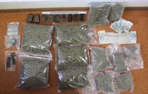 Zabezpieczone przez policjantów środki odurzając- w foliowych workach susz marihuany, haszysz wagi, elektroniczne i pieniądze