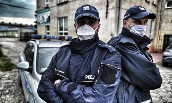 Policjanci stoją przed radiowozem