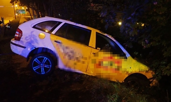 samochód, który do połowy znajduje się w przydrożnym rowie, a druga połowa wystaje na chodnik