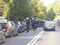 sznur aut stojących na pasie jezdni i policjanci w hełmach i kamizelkach kontrolują kierowców