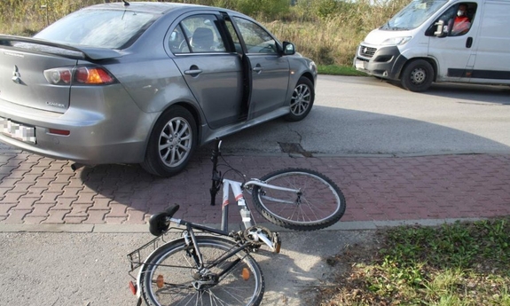 samochód stojący w poprzek jezdni, obok leży rower