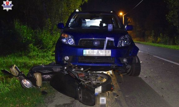 Na miejscu wypadku wywrócony skuter i niebieski samochód