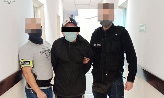 zatrzymany mężczyzna trzymany przez policjantów